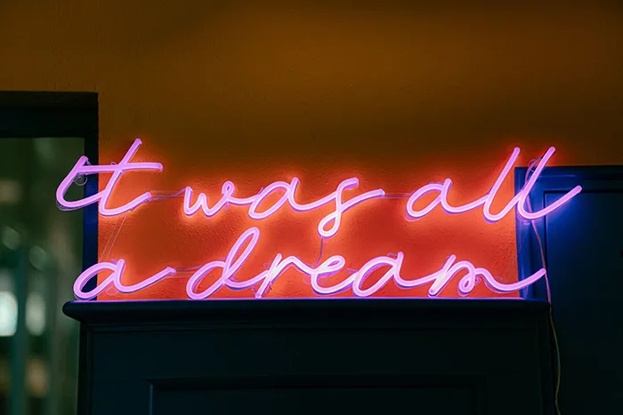Roze neonbord met de tekst "it was all a dream" in een donkere ruimte.