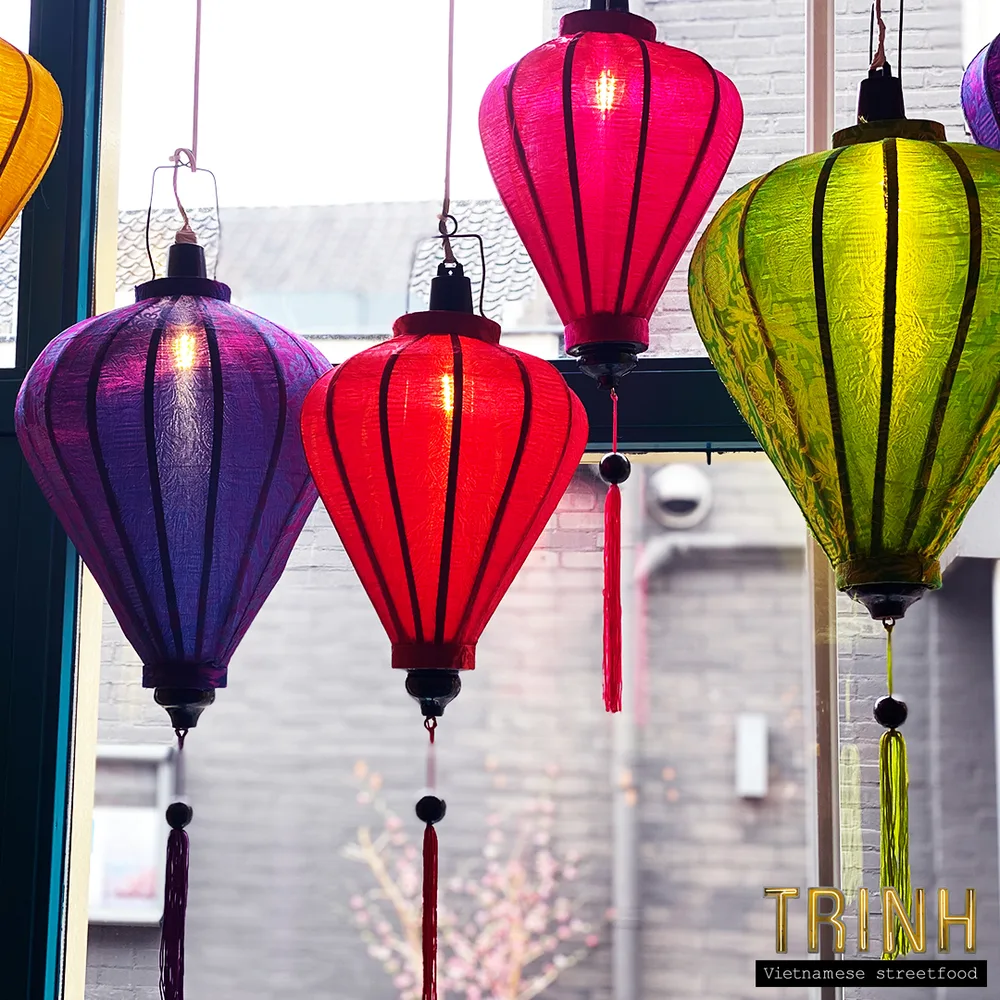 Paarse, roze, rode en groene Vietnamese zijden lampions voor een raam.
