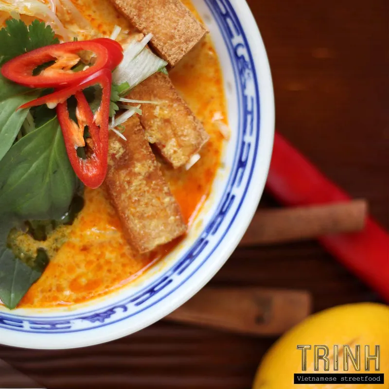 Kom pittige currynoedelsoep met tofu, rode peper en Thaise basilicum, van bovenaf.