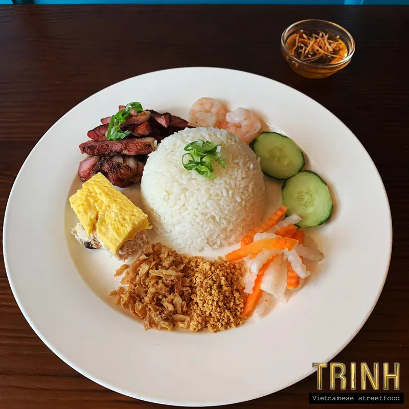Bord cơm tấm: gegrild varkensvlees, garnalen, omelet, jasmijnrijst, komkommer en zoetzure wortel.