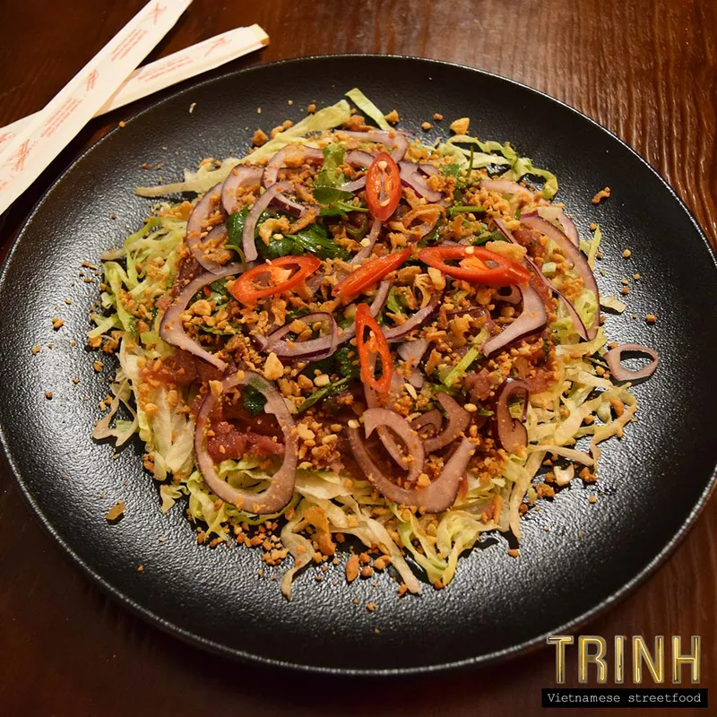 Zwart bord met bò tái chanh — Vietnamese rundercarpaccio met rode ui, pinda's en peper.