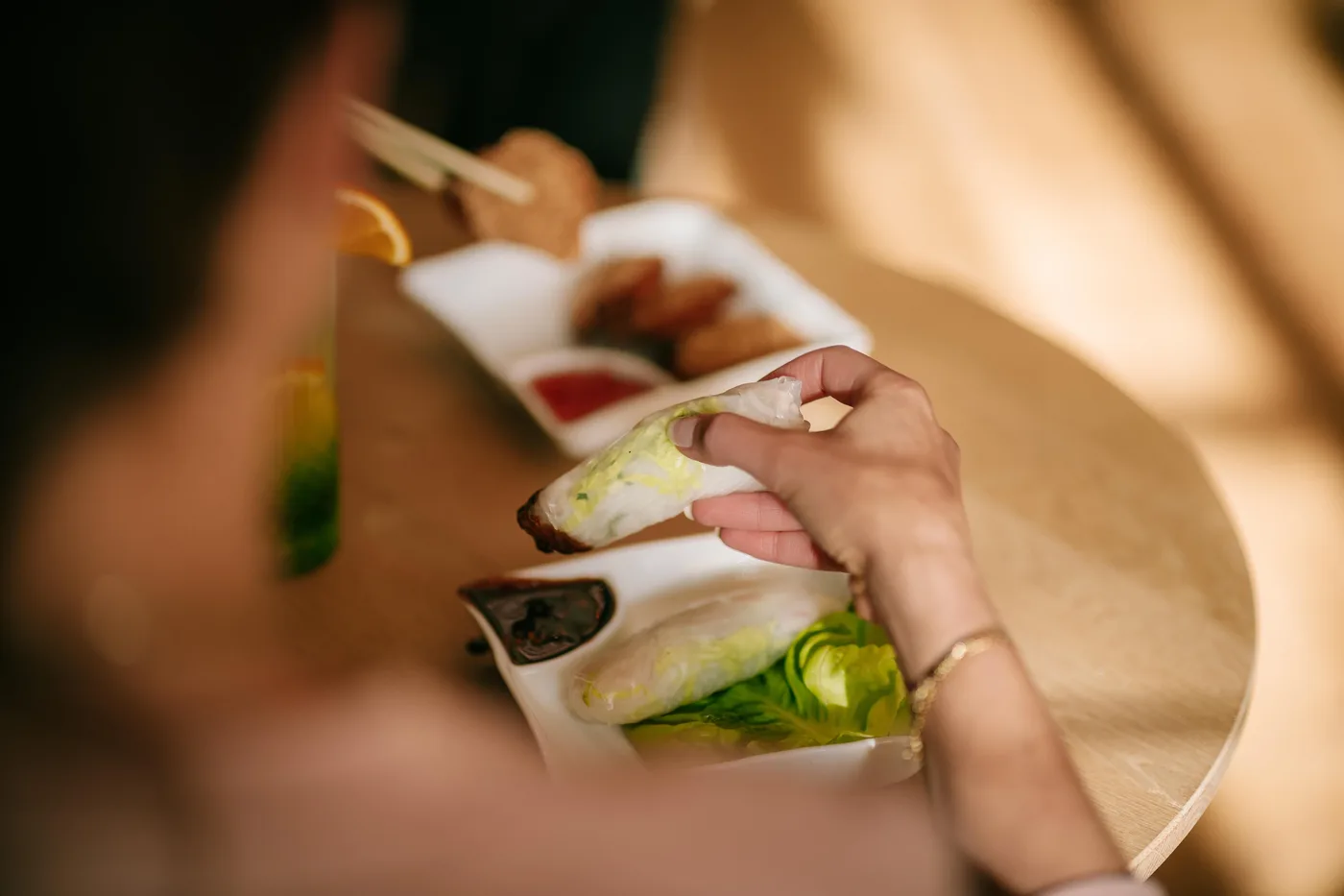 Handen rollen verse rijstpapierrolletjes met vlees en sla.