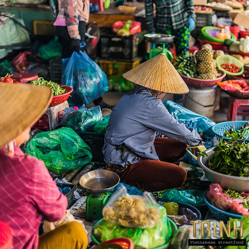 Vietnamese markt: verkoopsters met kegelhoeden tussen kratten groente en fruit.