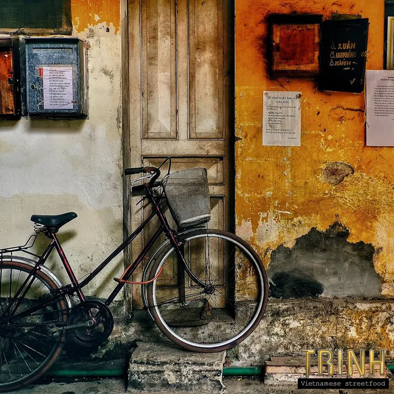 Fiets tegen een verweerde okergele muur met houten luiken in Vietnam.